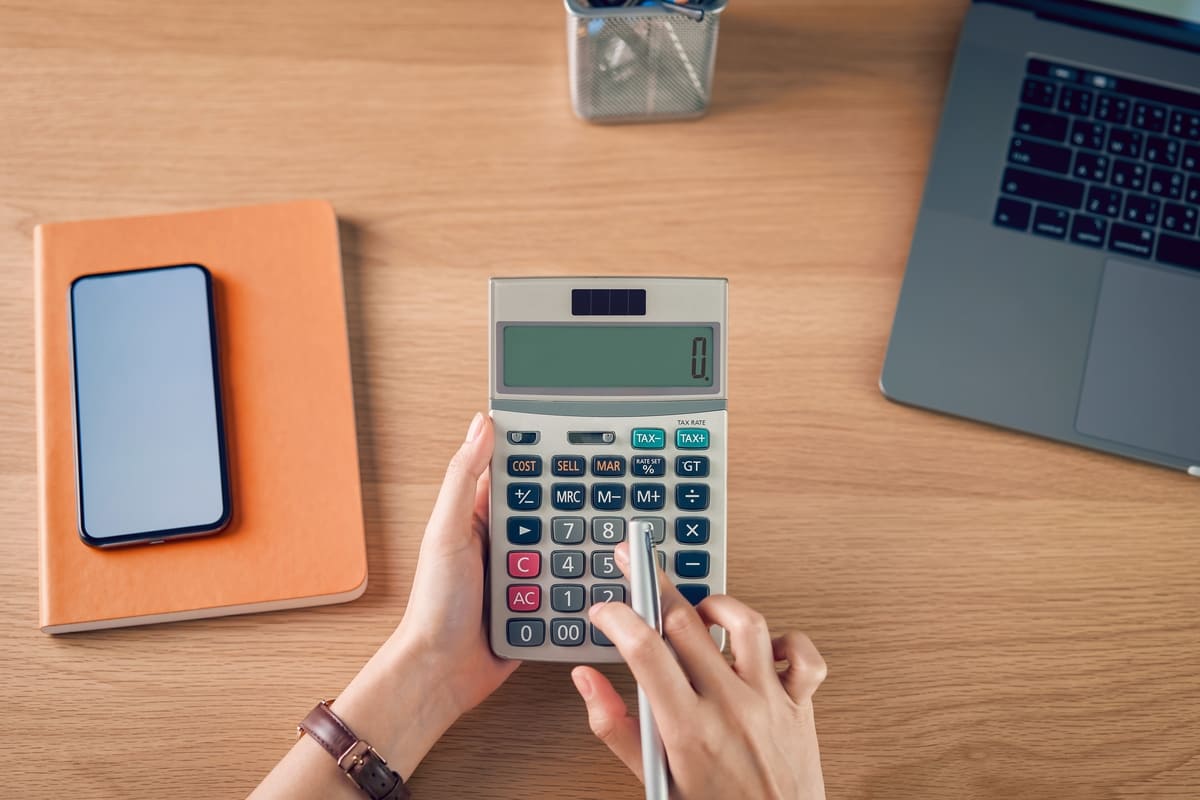 A woman holding a caluclator at her desk