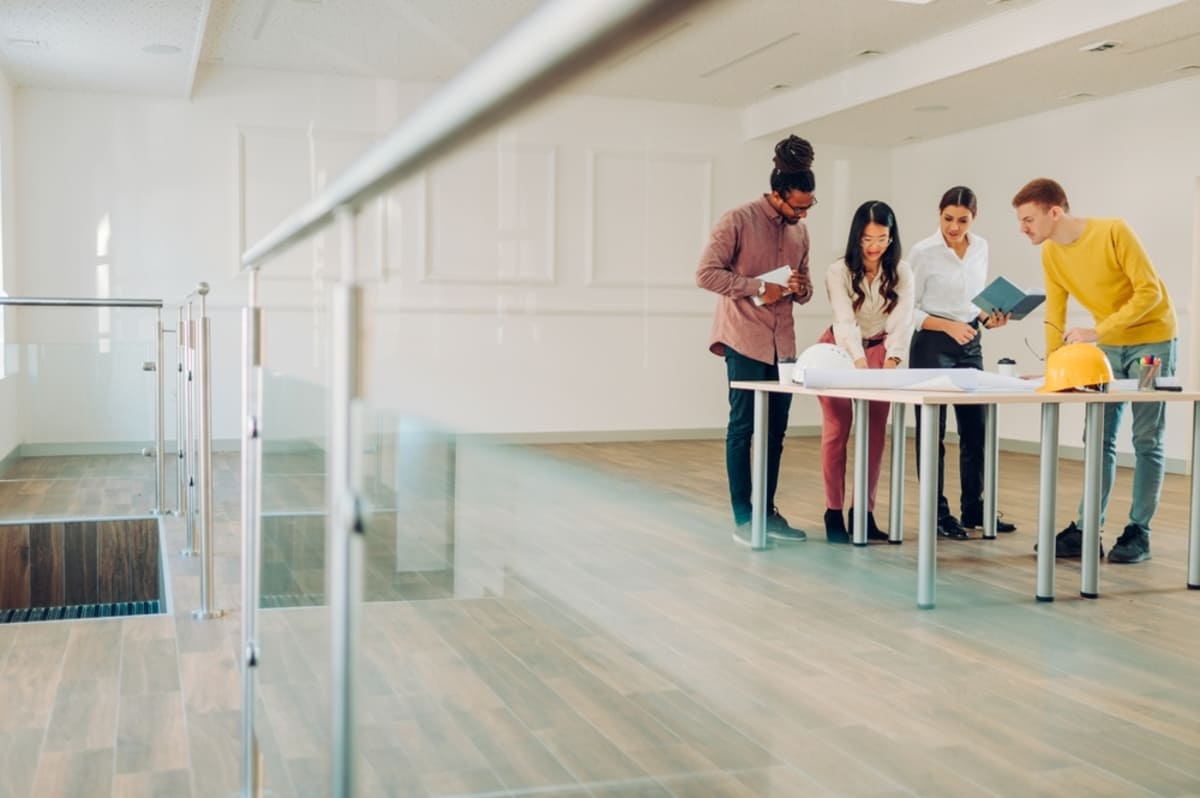A group of people reviewing building plans in an empty office space, tenant improvement concept