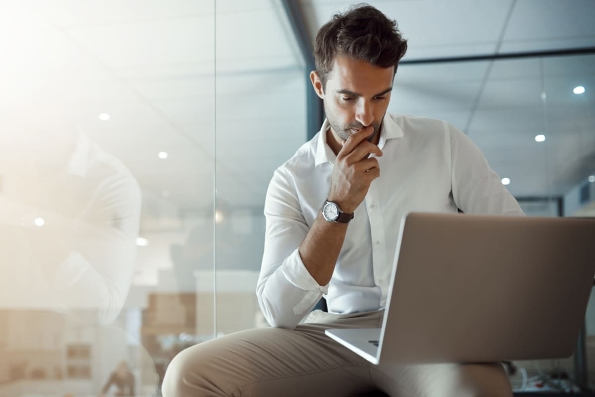 Businessman sitting with laptop carefully considering business options (1) (1)