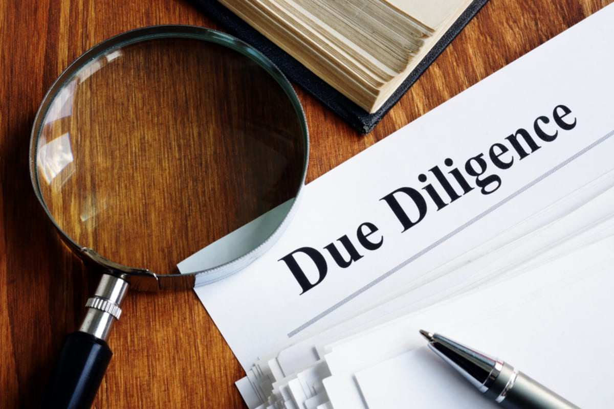 Due Diligence written on a paper next to a magnifying glass