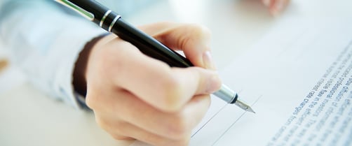 Person holding a pen about to sign a contract