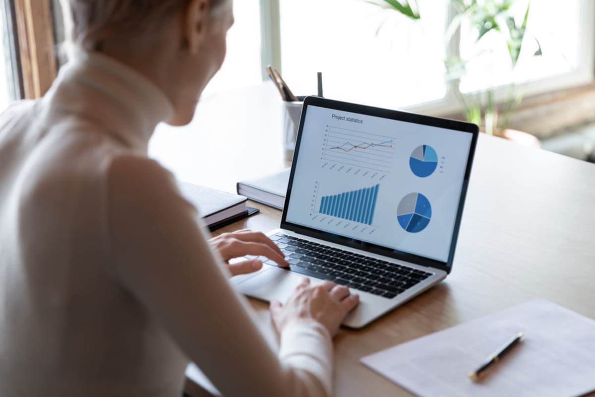 Rear view close up businesswoman working with financial project statistics on laptop