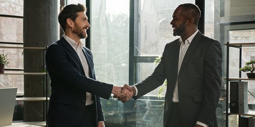 Two businessmen shaking hands in commercial office building