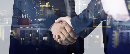 Two businessmen shaking hands with a city in the background
