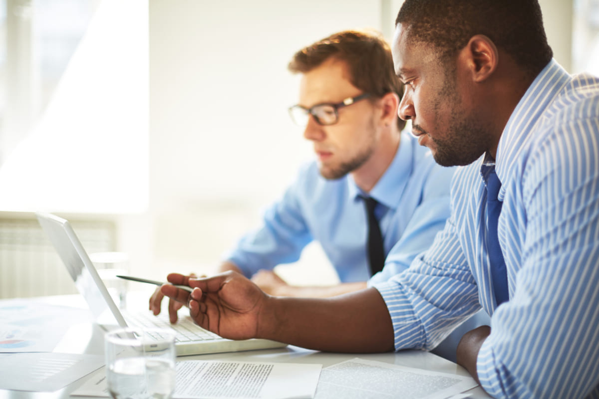 Two businessmen working at a laptop, property management technology concept