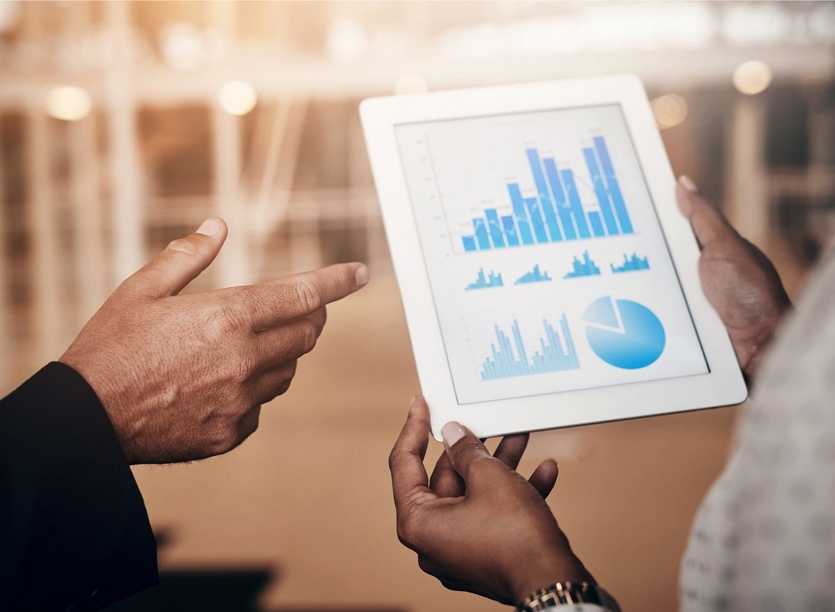 Two people reviewing charts and graphs on a tablet