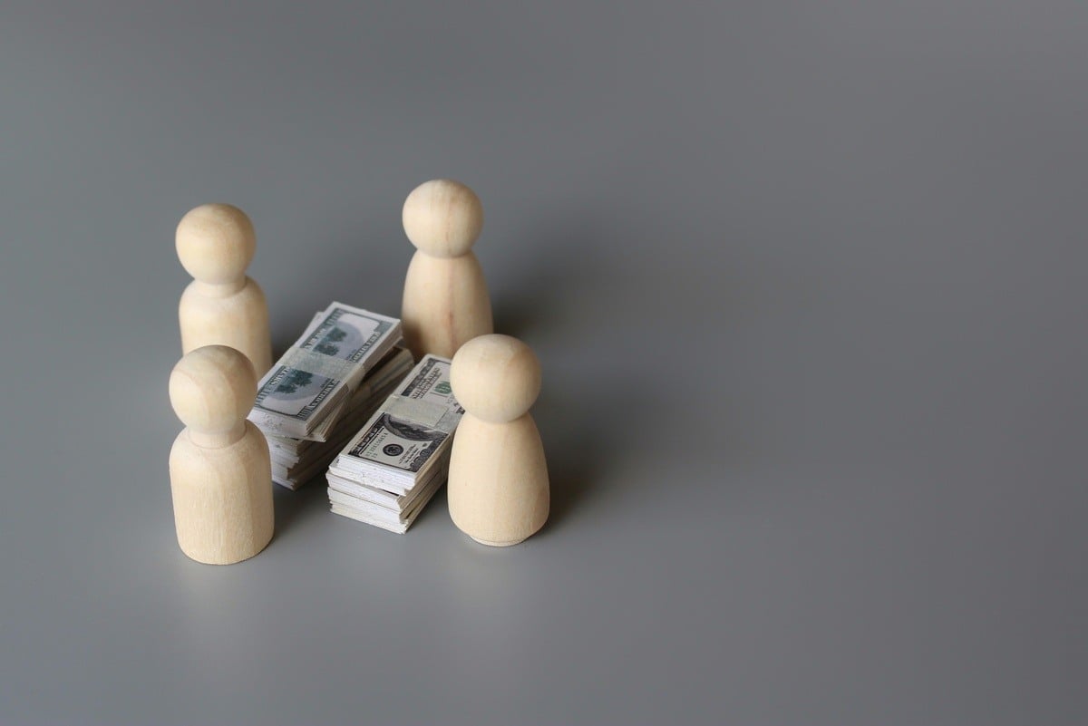 Wooden figures around a stack of money