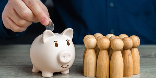 Wooden figures with a man putting a coin a piggy bank
