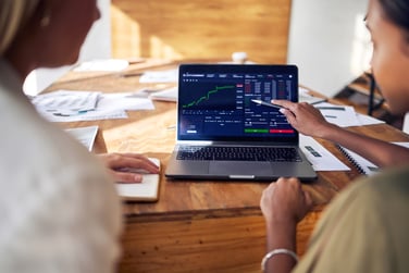 This image features a computer with the stock market analysis to represent commercial real estate vs stock market. 
