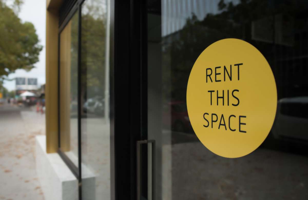 A yellow sign stating rent this space on glass, rentable vs. usable space concept
