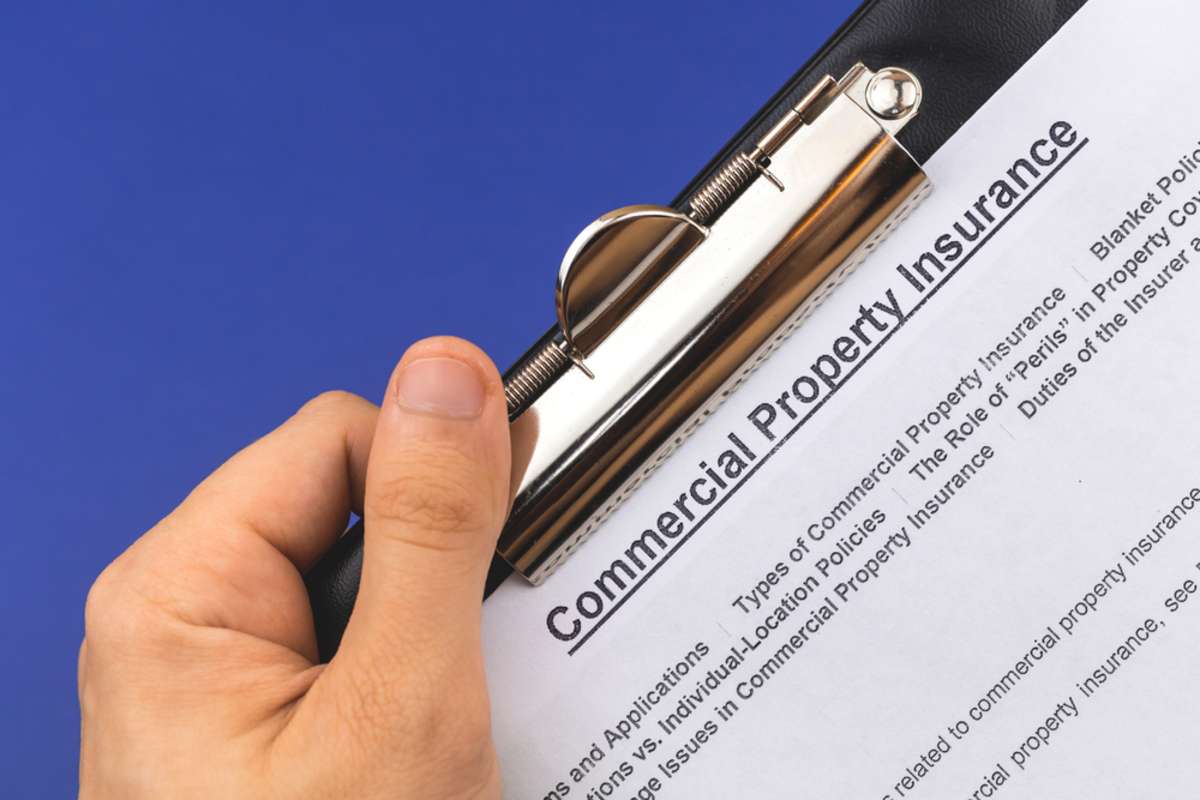 Hand with commercial insurance document on clipboard, leasing commercial space concept