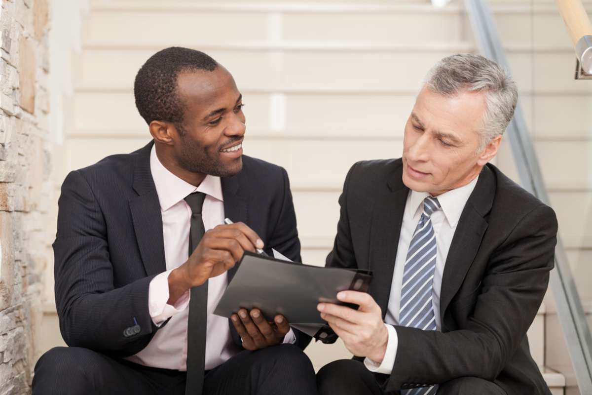 Two businesspeople sitting on stairs and looking at papers