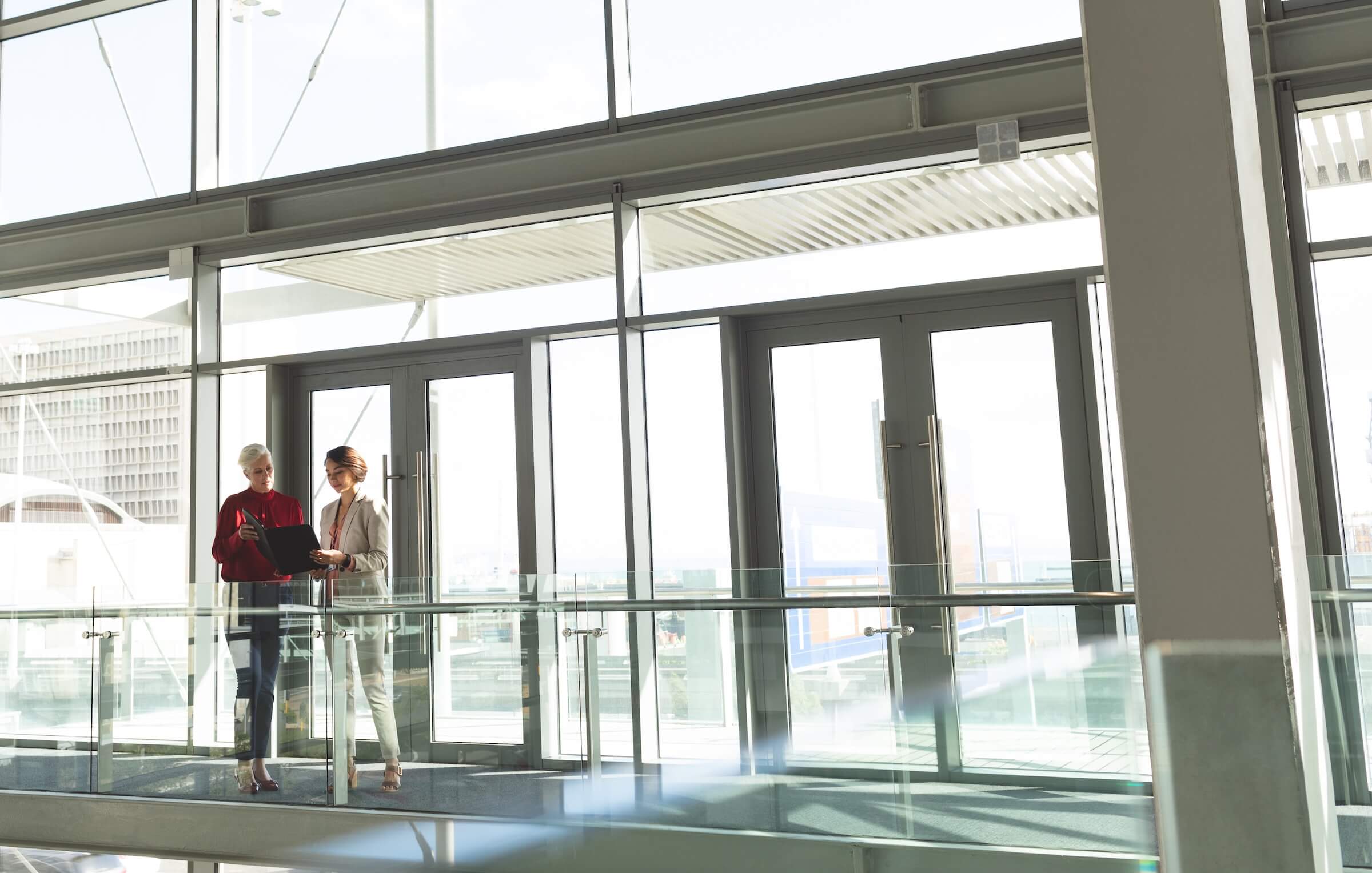 Two businesswomen discussing commercial real estate contract in office building