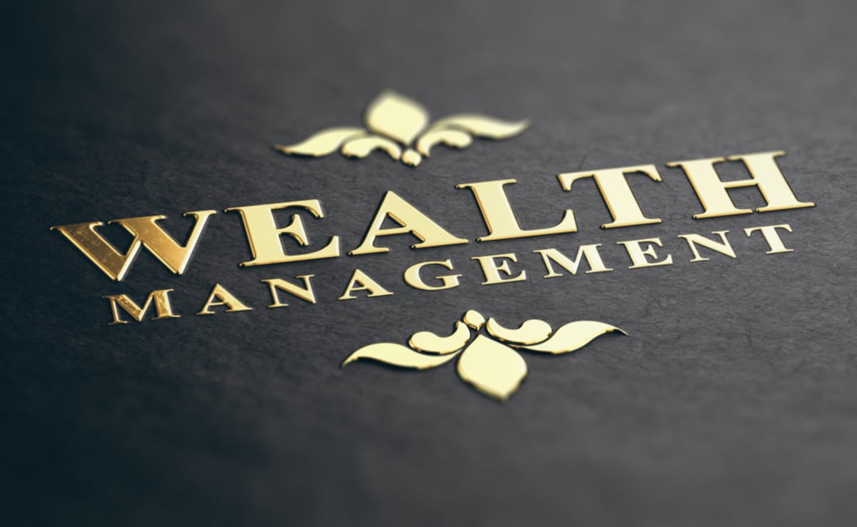 Wealth management phrase embossed with gold foil on black paper background.