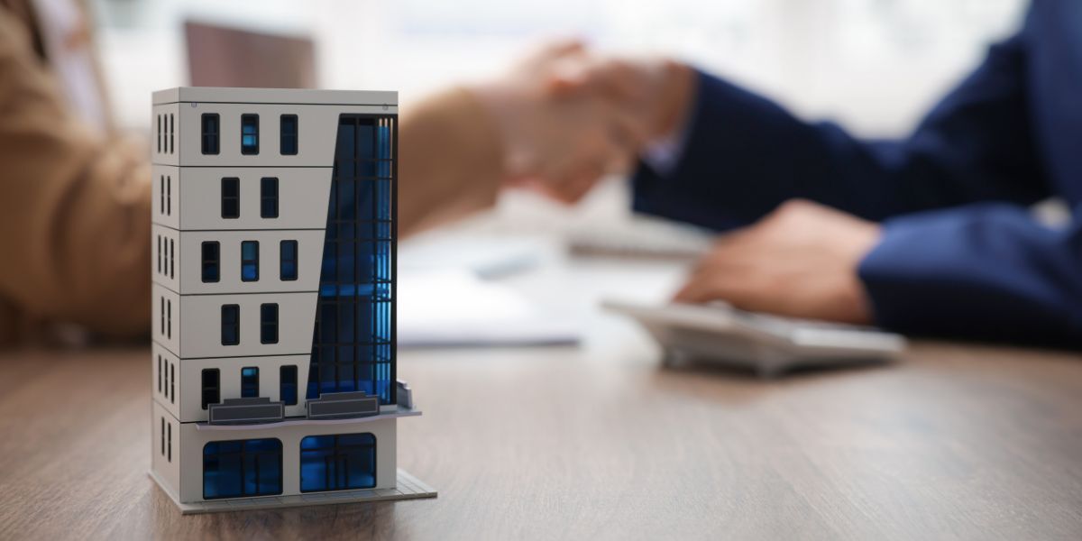 01 Real estate agent and client shaking hands at desk in office