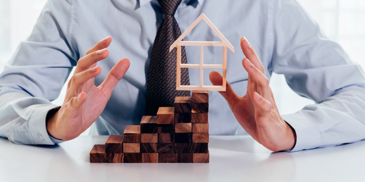 2 businessman using hand to protect  house and real estate building