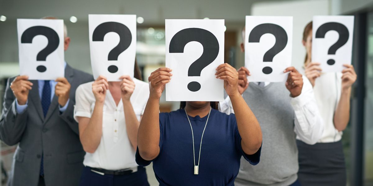 7 Shot of a group of businesspeople holding questions marks in front of their faces