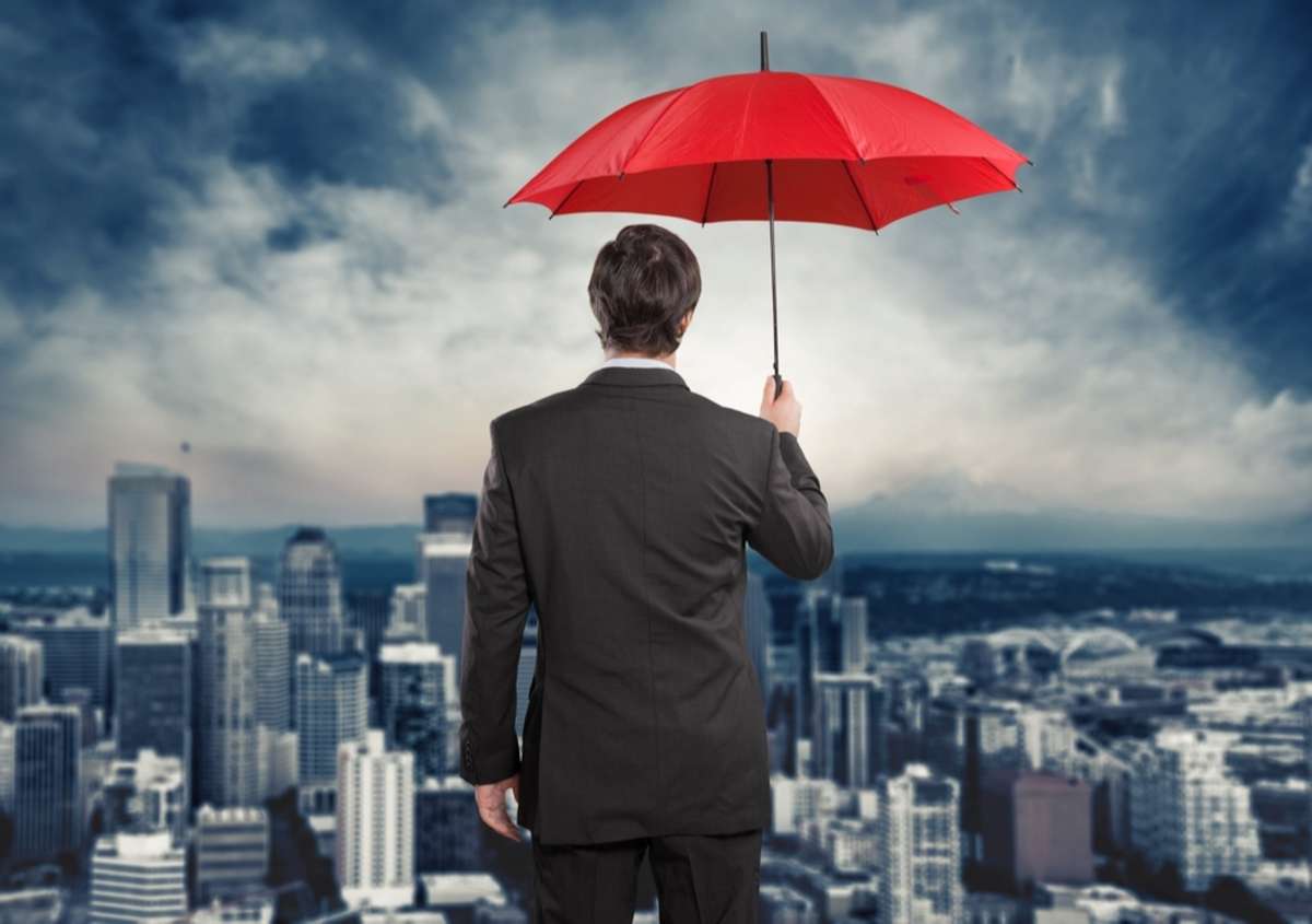 Man under an umbrella looks out over buildings, commercial tenant renters insurance concept